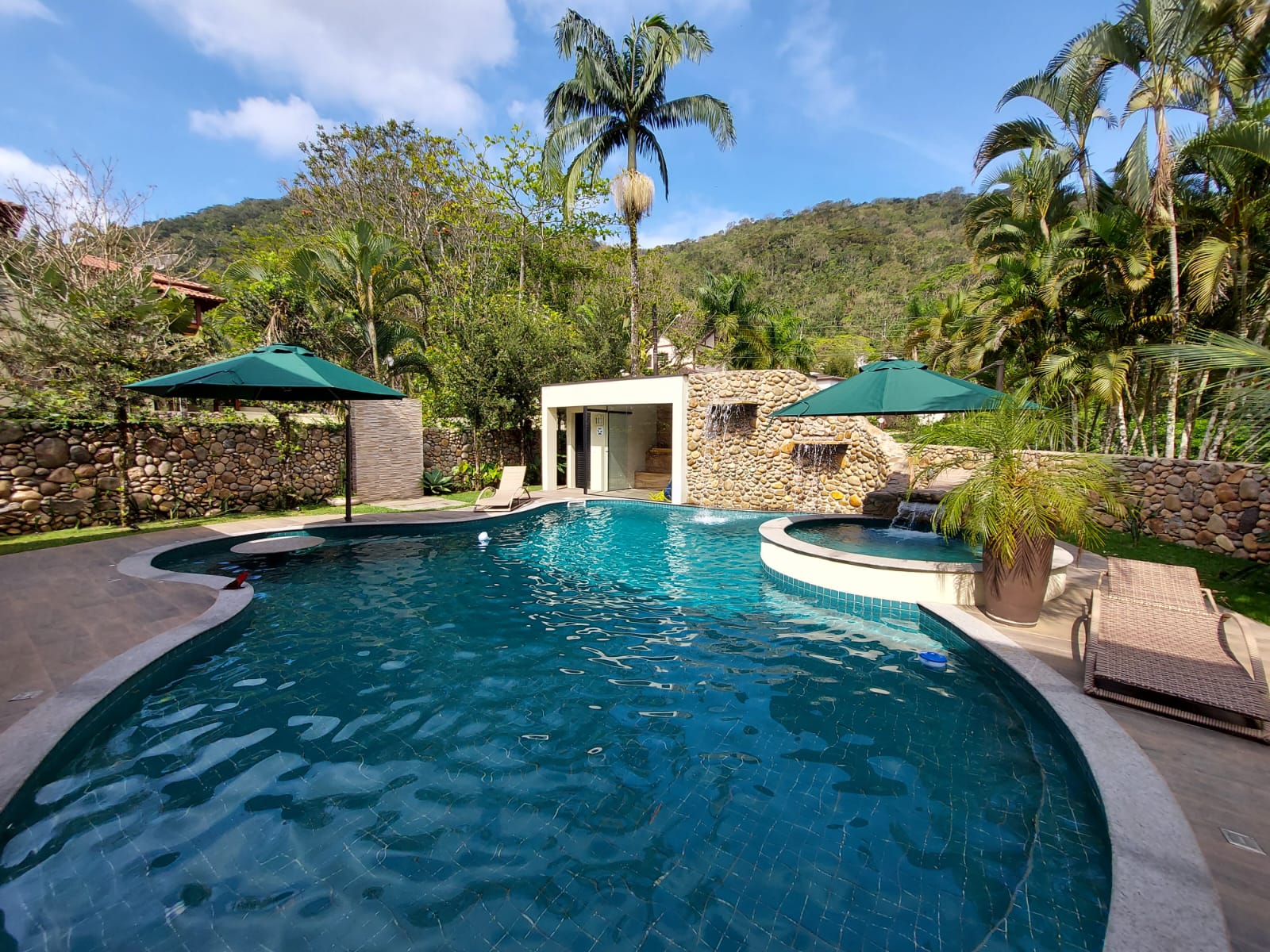 Área de piscina com dois ombrelones verdes